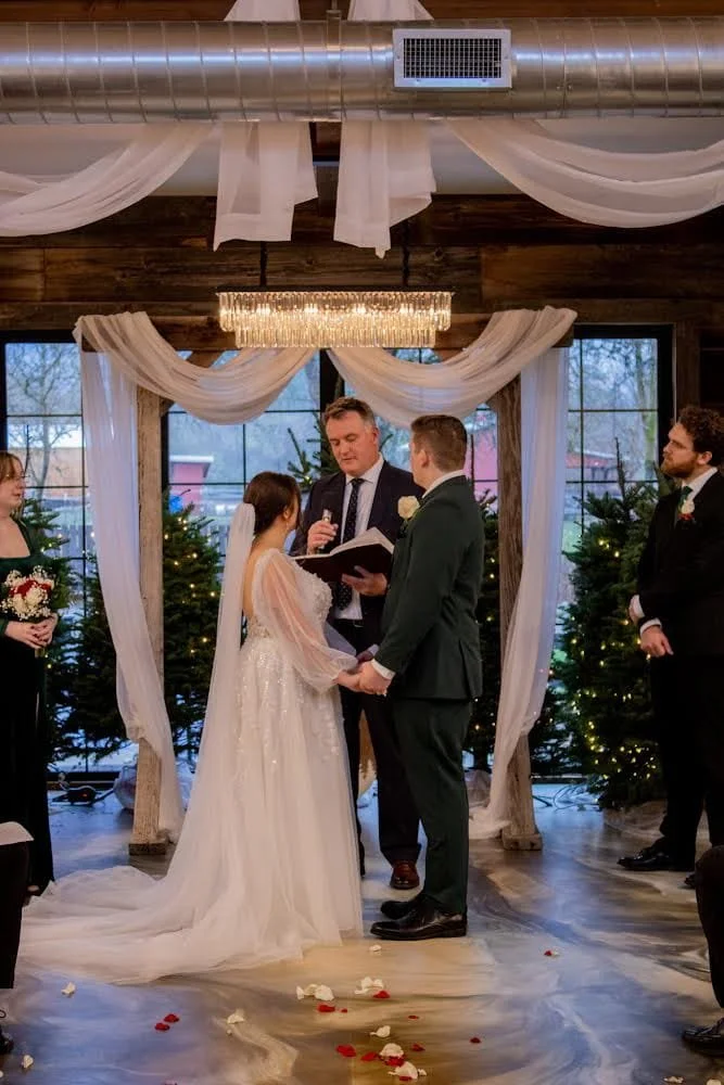 Decorative birthday setup with a vintage horse-drawn carriage, large illuminated number 3, floral arrangements, a unicorn cutout, and a sign that says "Happy Birthday," inside a wooden room with pink and white hanging decorations and windows.