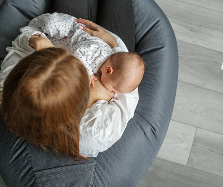 mother breastfeeding baby sitting on gray couch