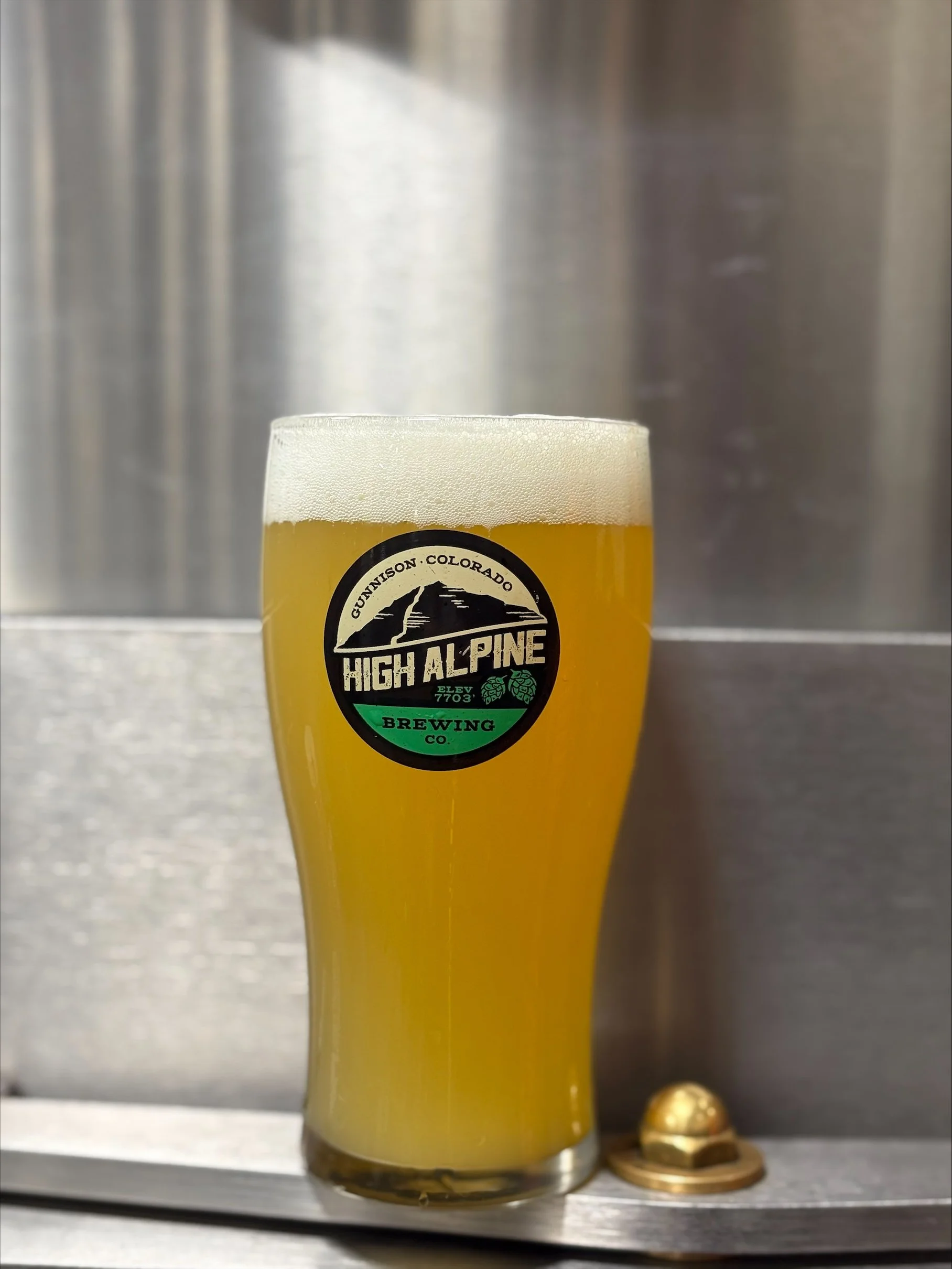 hazy ipa beer in pint glass sitting on a stainless steel ledge