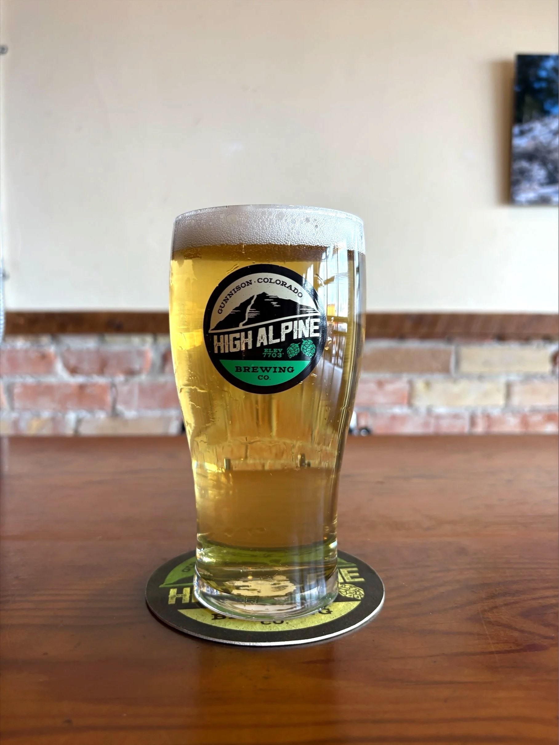 Helles in Paradise lager in pint glass on wooden table