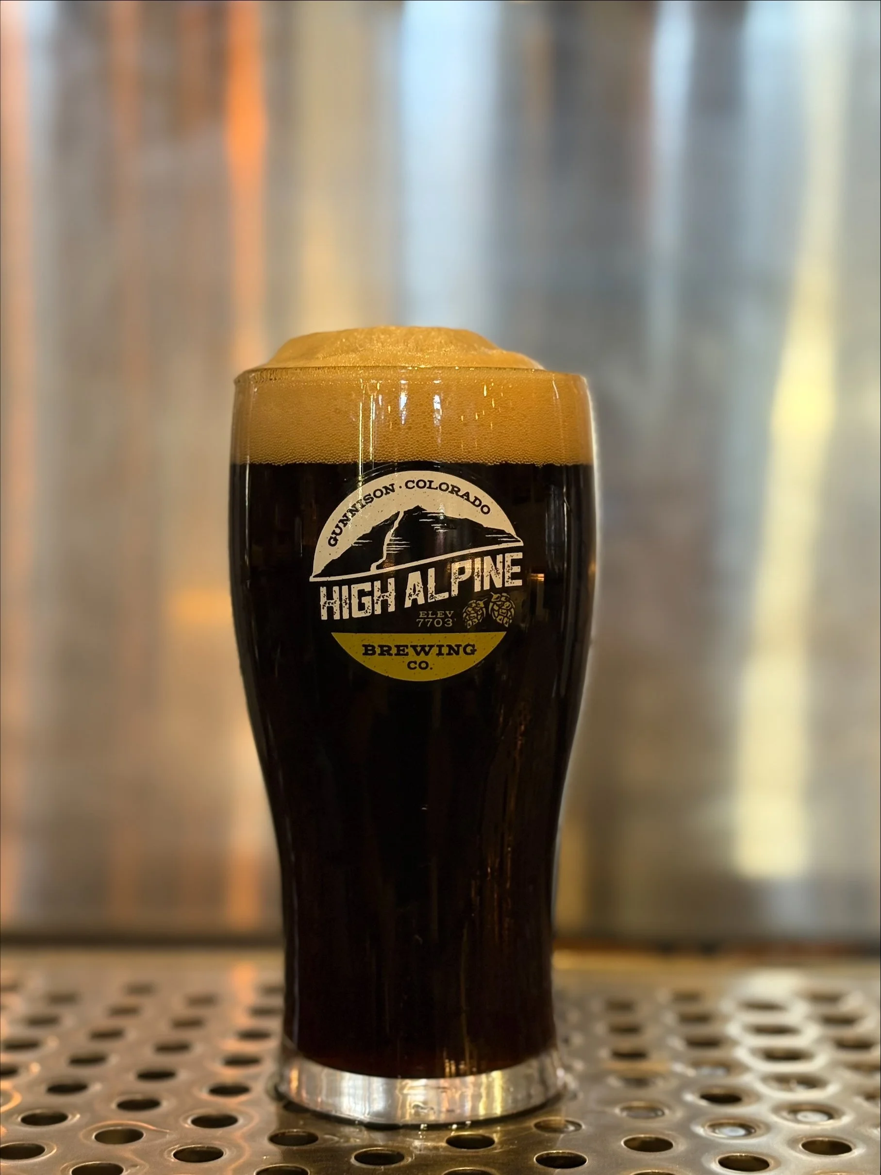 beer in pint glass on stainless steel bar back with stainless background