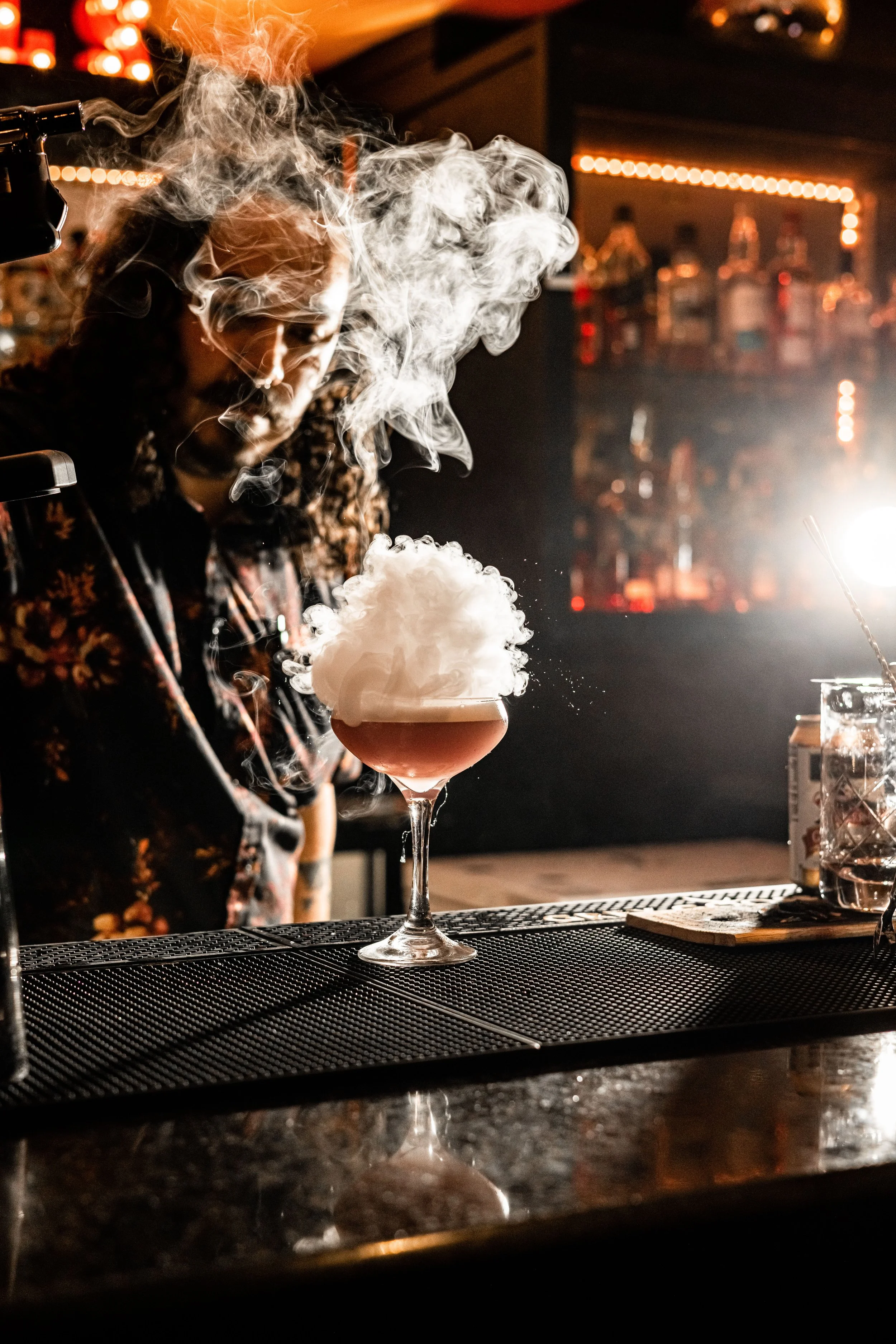 Cocktail with smoke effect on bar counter in dimly lit bar