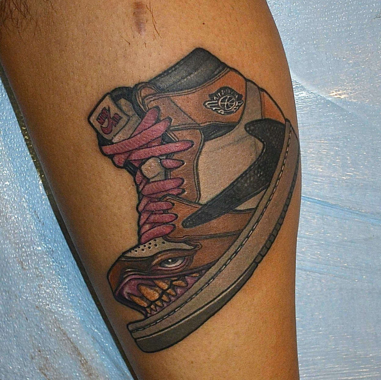 New school tattoo of a nike travis scott sneaker with a skull design on the toe and pink laces.