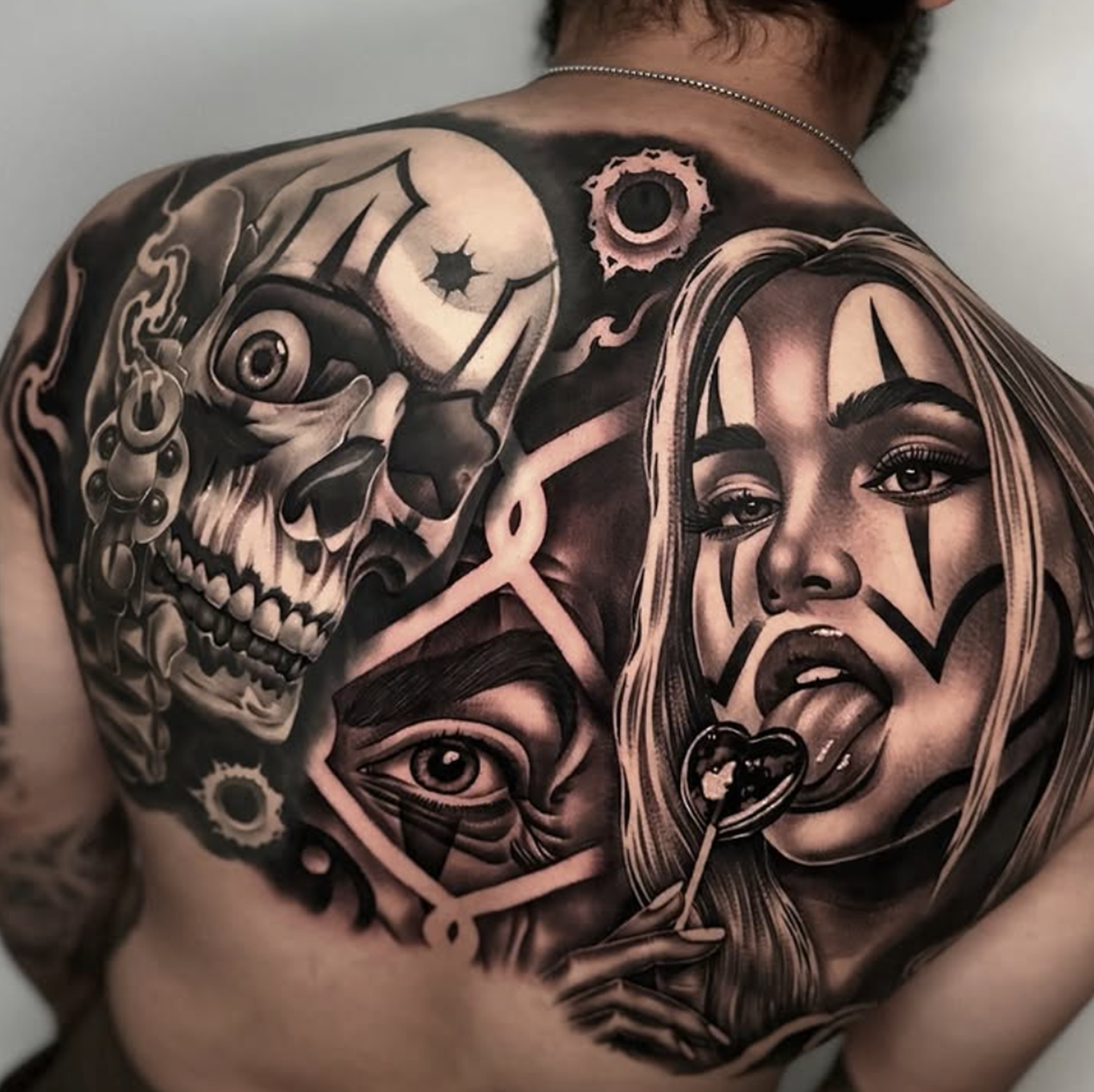 Black and gray tattoo featuring a skull, a woman's face with long hair and lipstick, and various abstract designs and eyes.