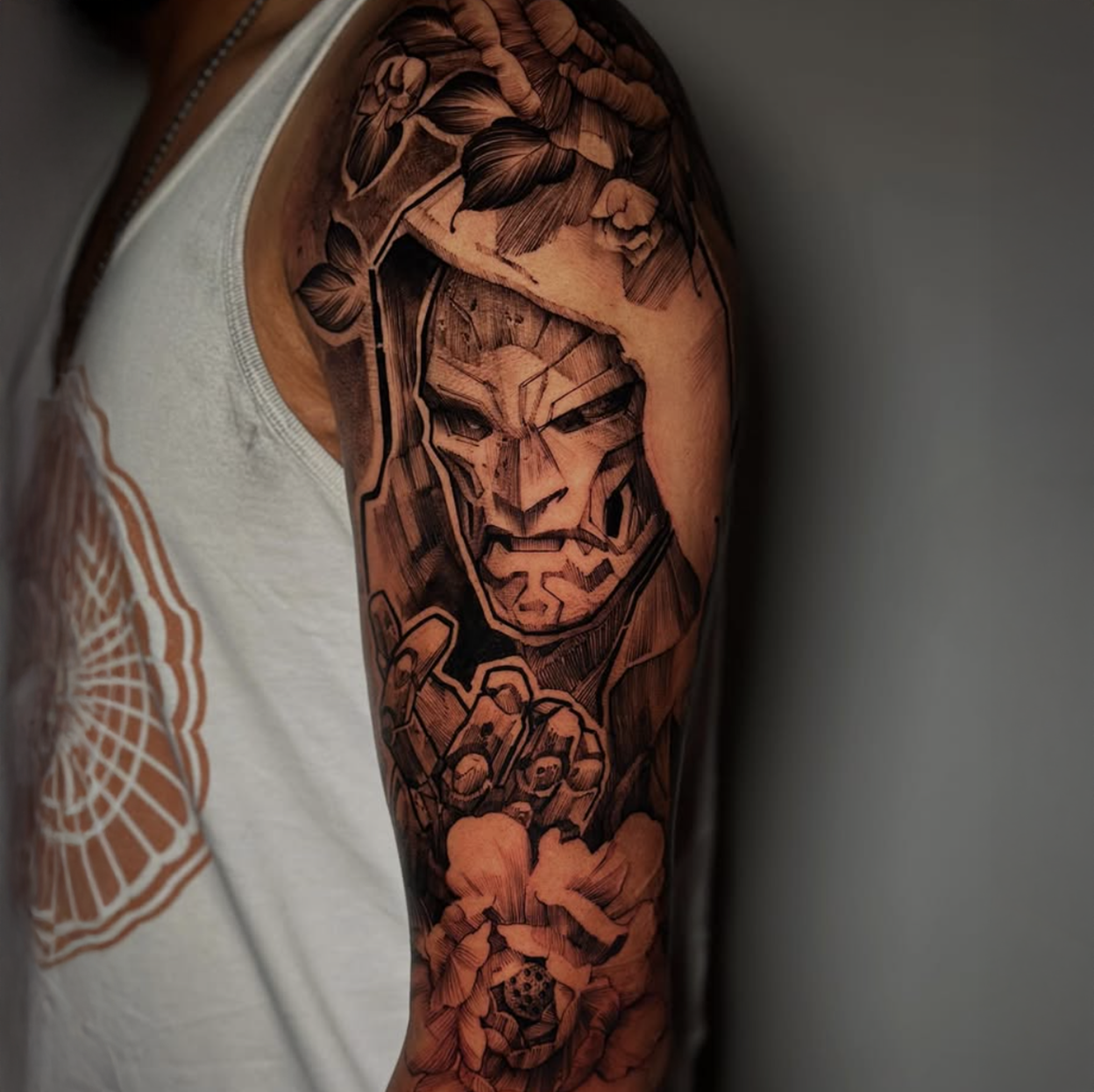 Tattoo of a fierce, stylized features on a person's upper arm, surrounded by floral and geometric designs.
