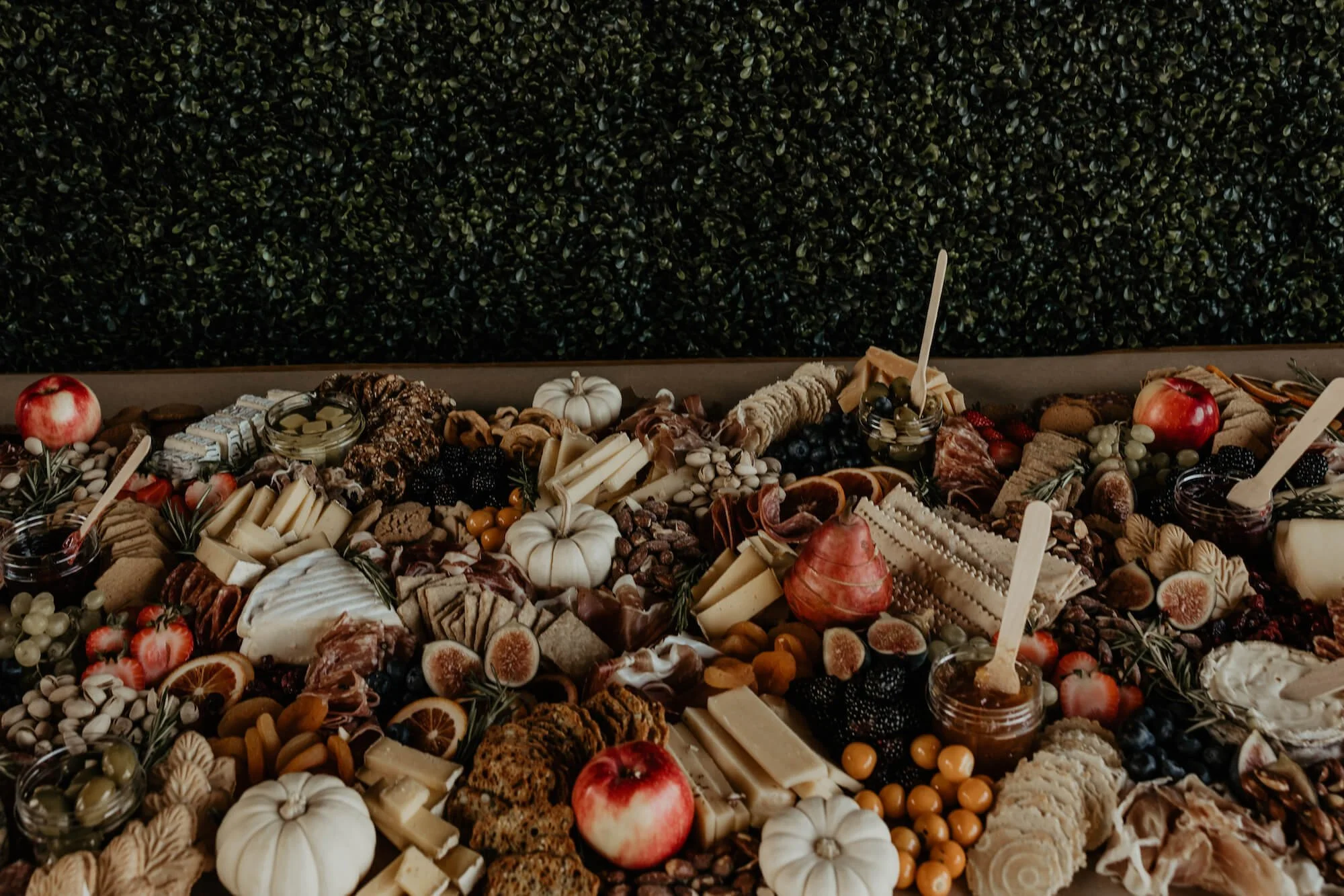 A cheese and fruit board with pumpkins, apples, grapes, cookies, and jams.