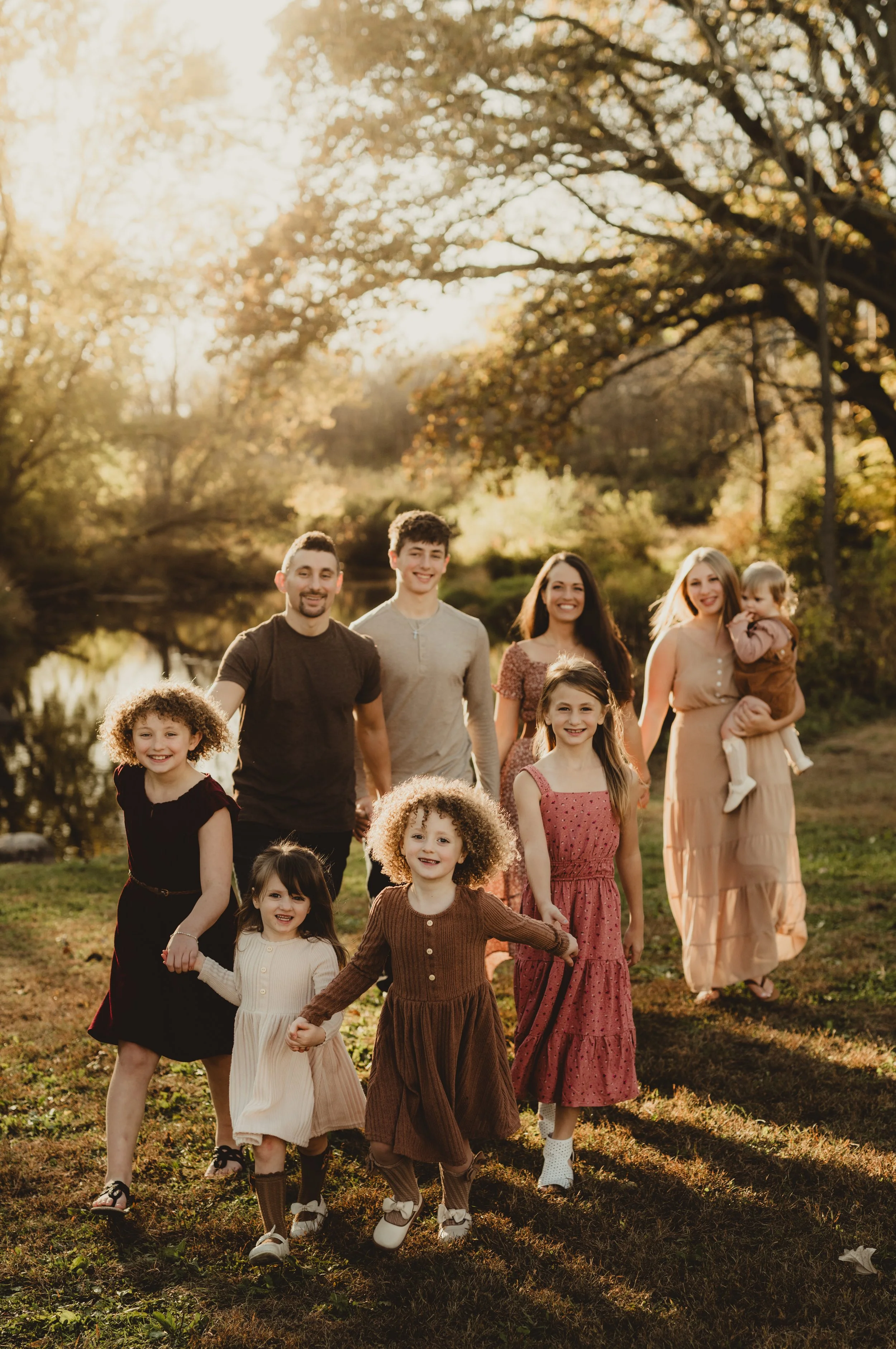 Family group walk in park during autumn; children and adults smiling.
