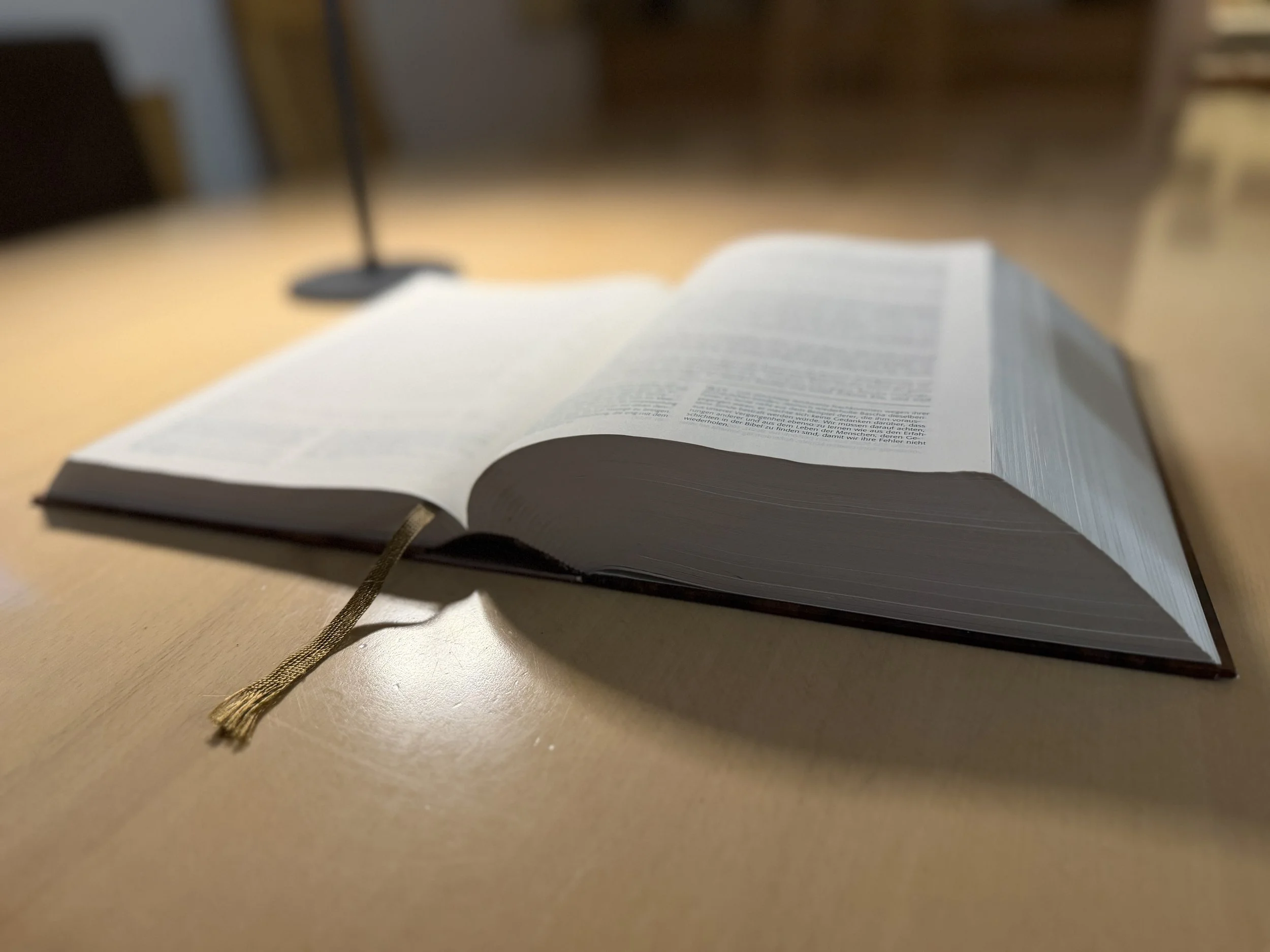 A opened Bible on a table with dimmed light.