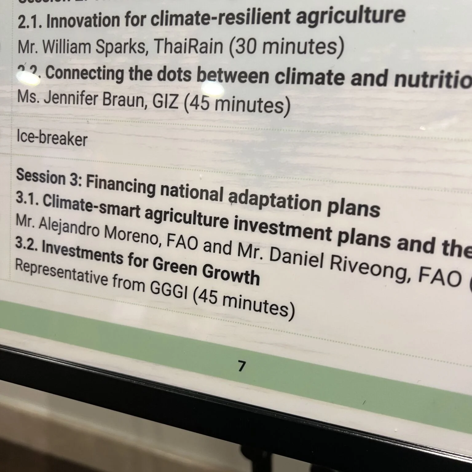 Close-up of a conference agenda or program listing sessions and speakers with topics on climate-resilient agriculture, connecting the dots between climate and nutrition, and financing national adaptation plans, including names of speakers and session durations.