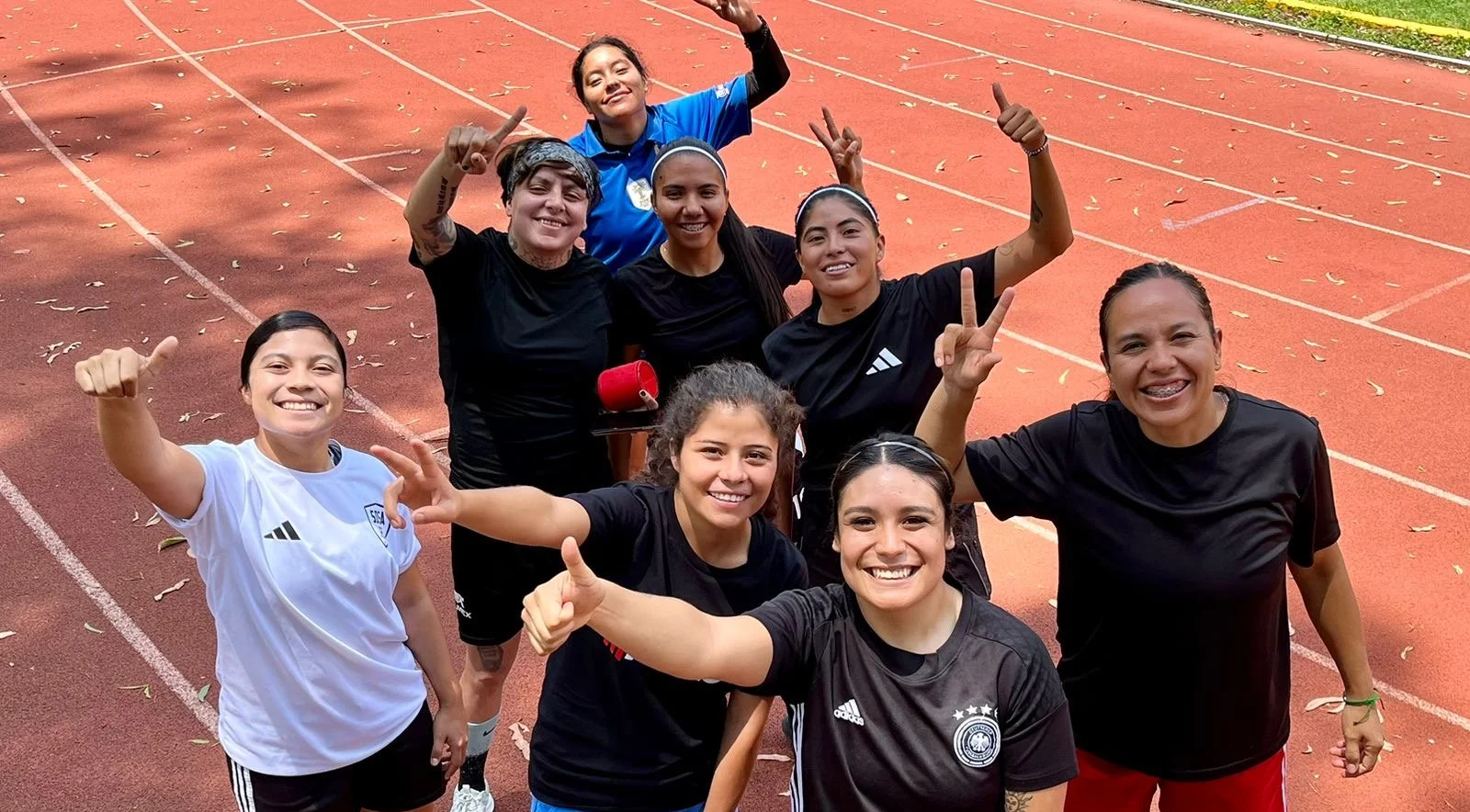 Female players smiling at the camera showing their thumbs up and peace signs