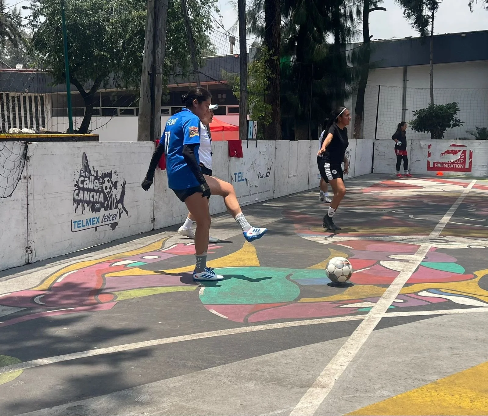 Female players training on concrete pitch.