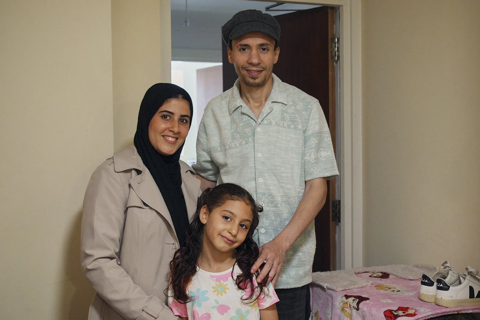 Image of a Father, Mother and daughter standing in their home, smiling at the camera