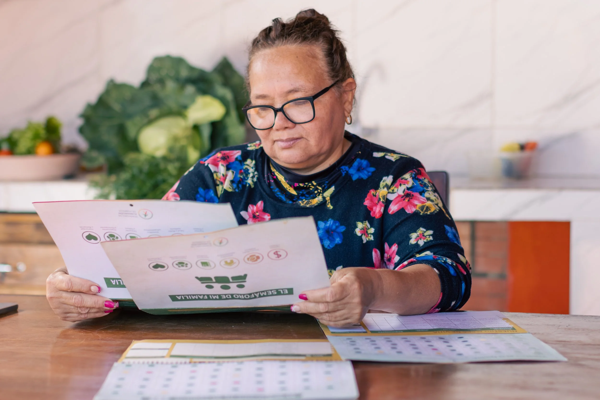 Middle-aged woman sitting at a kitchen table reading Poverty Spotlight documents