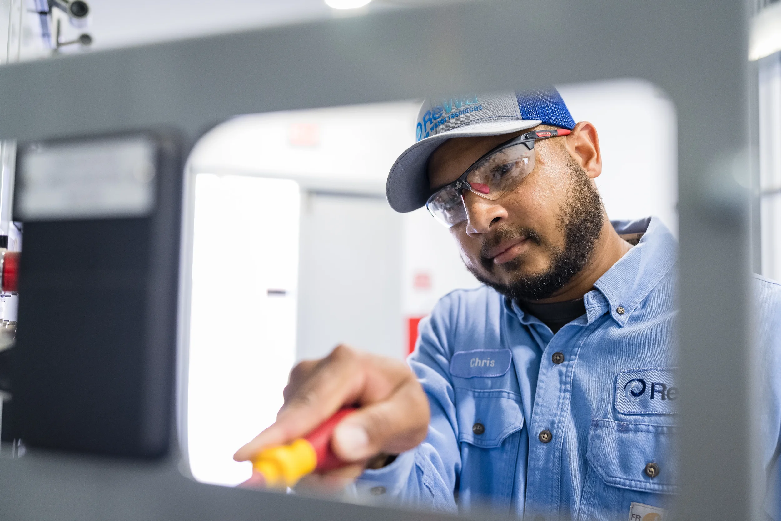ReWa utility worker in safety glasses focused on technical equipment at a jobsite