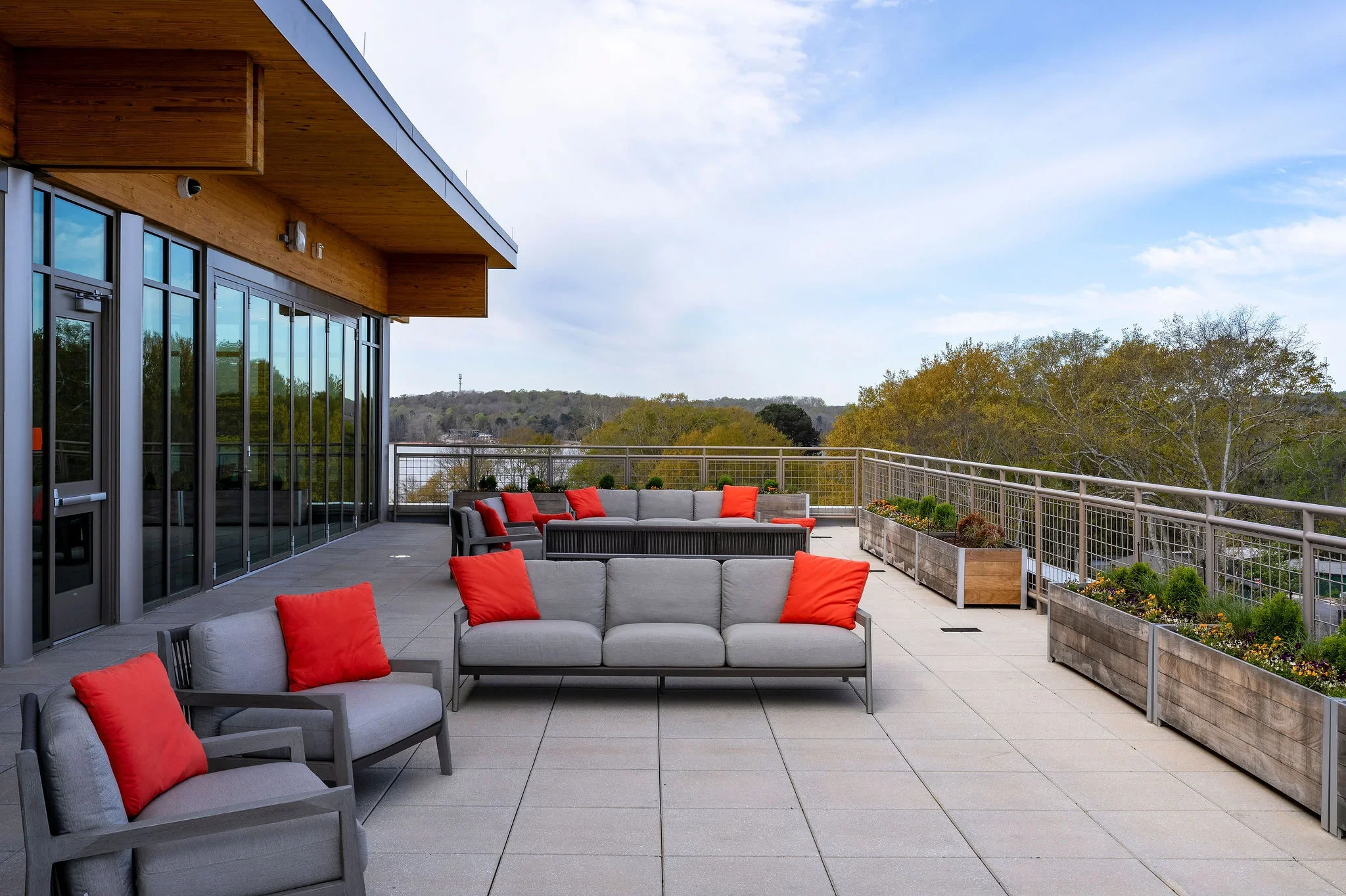 Outdoor seating area on the Clemson Alumni Center terrace with planter boxes, railings, and views beyond the building.