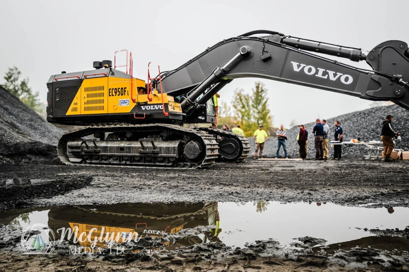 Experienced construction photographer documenting an active jobsite with a Volvo excavator and crew working nearby