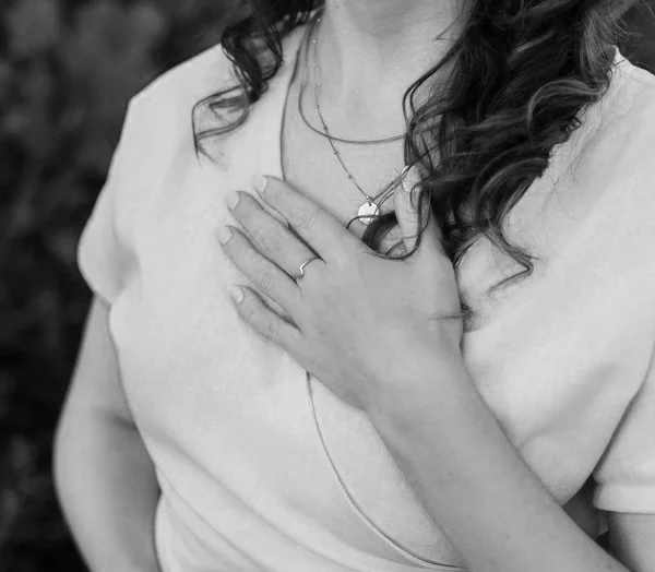 Black & white photo of a woman with her hand over her heart.