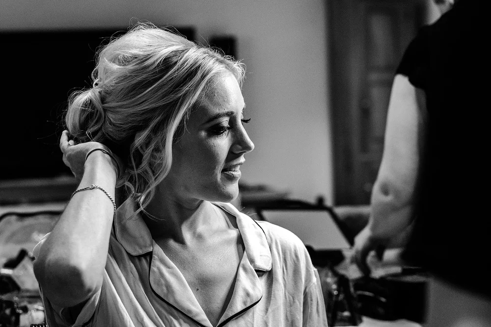 Black and white portrait of Katie having her hair finished before the ceremony