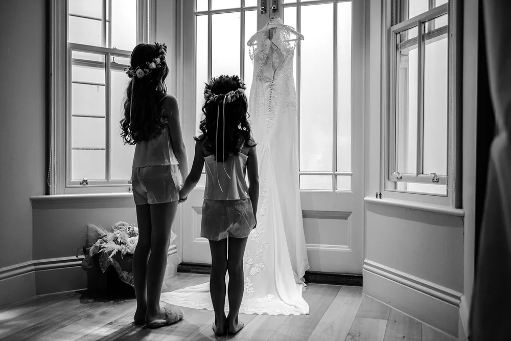Katie in her wedding dress with a flower girl at the window before leaving for Fulham