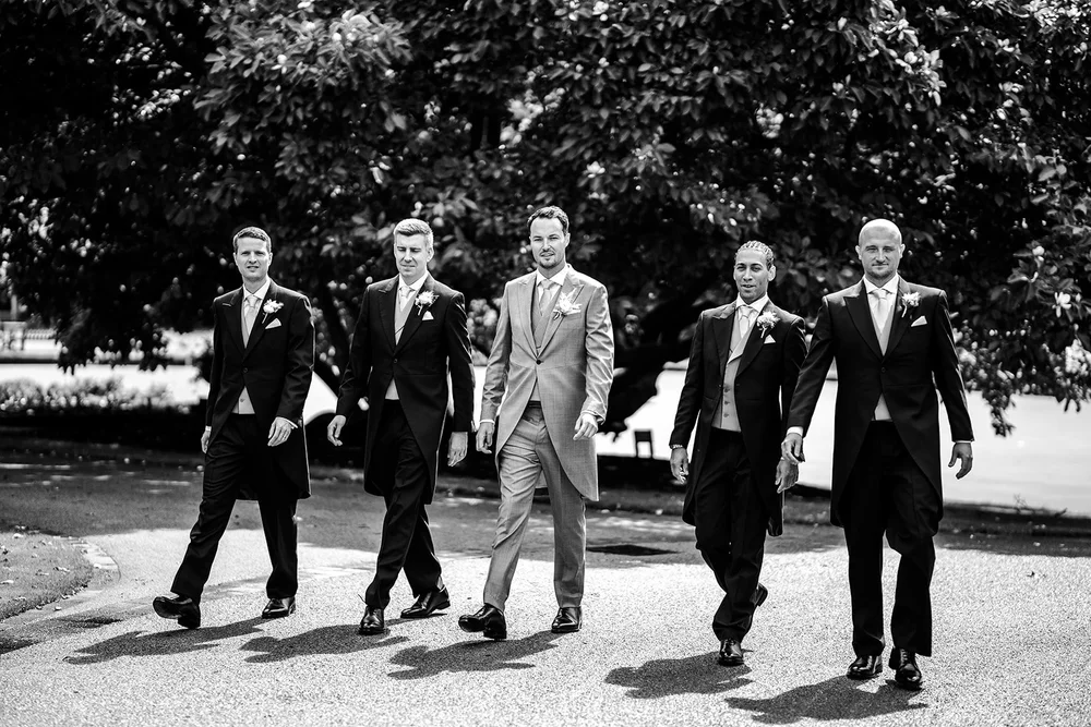 Black and white photograph of the groomsmen walking through the grounds at The Hurlingham Club