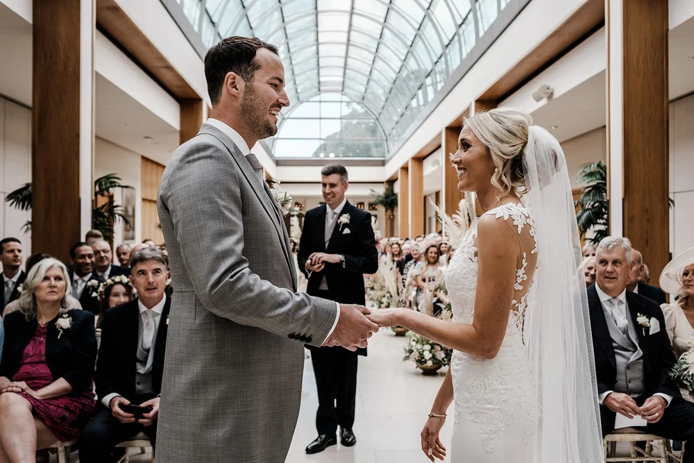 Mike and Katie exchanging rings under the glass roof of the Palm Court
