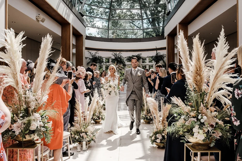 Pampas grass and dried flowers framing the ceremony aisle in the Palm Court
