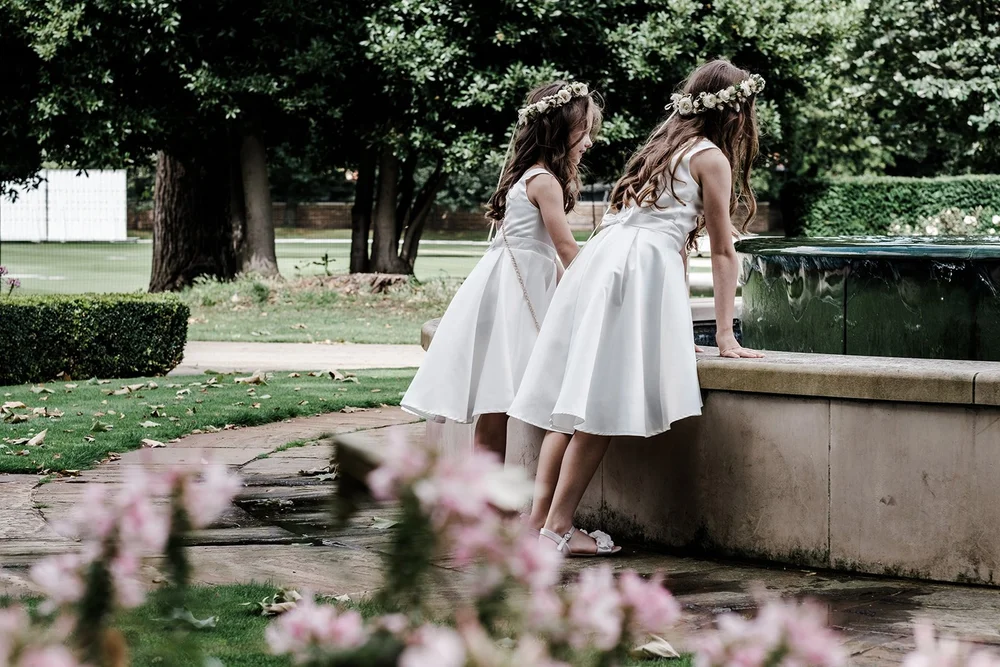 A flower girl leaning over the fountain in the gardens at The Hurlingham Club