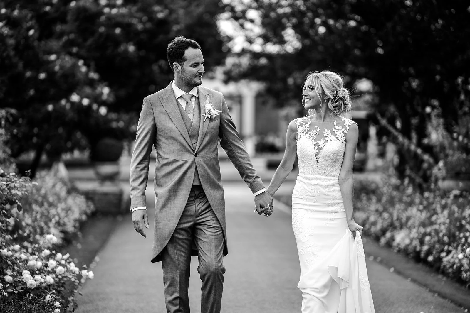 Black and white photograph of Mike and Katie walking hand in hand through the grounds