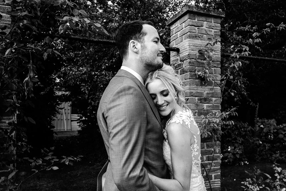Black and white photograph of Mike and Katie against the brickwork in the gardens