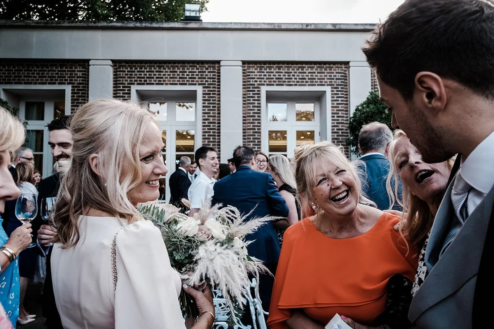 Black and white photograph of guests laughing together during the reception