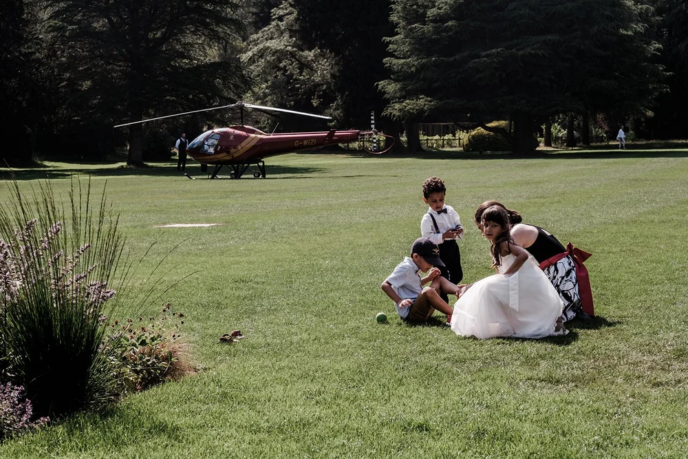 A red helicopter on the lawn at Grantley Hall with guests sitting on the grass
