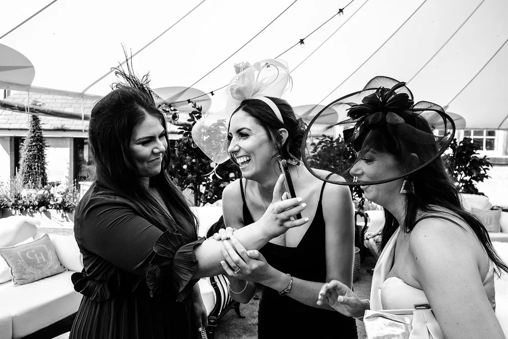 Black and white photograph of guests laughing together during the drinks reception