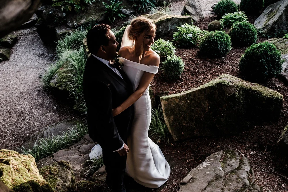 Bernie and Naesan holding each other in the gardens at Grantley Hall