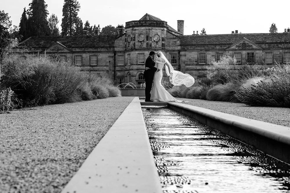 Black and white photograph of Bernie and Naesan beside the canal with the hall behind them