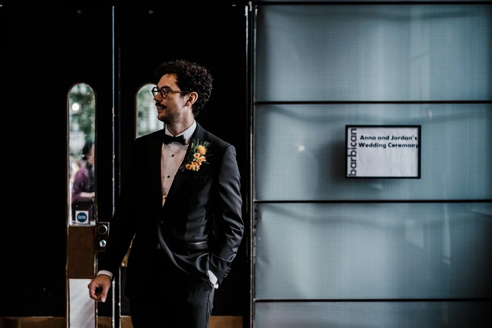 Black and white photograph of Jordan waiting in the concrete corridor at the Barbican