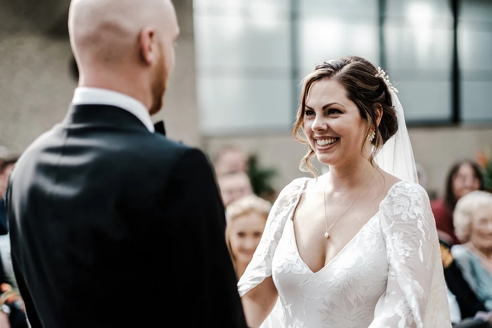 Anna smiling at Jordan during their wedding ceremony at the Barbican