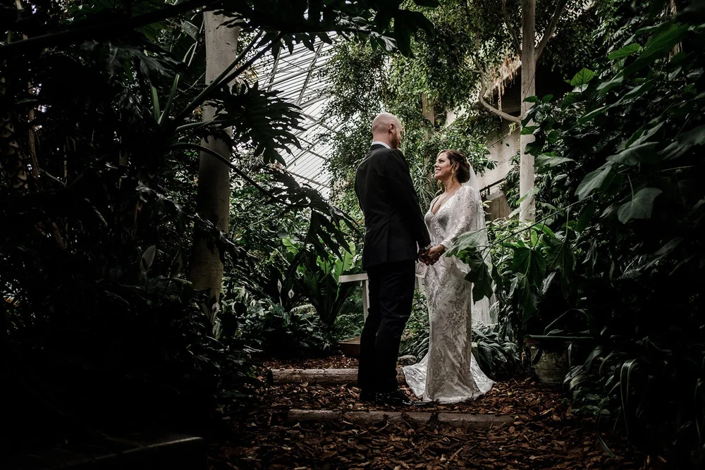 Jordan and Anna framed by tropical planting inside the Barbican Conservatory