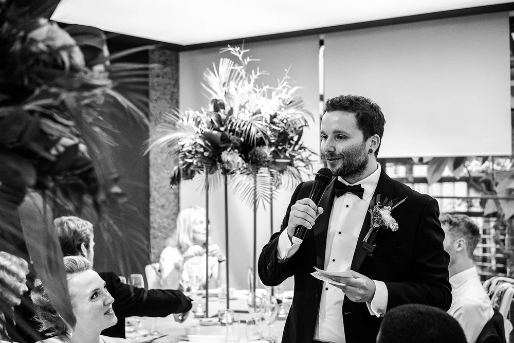 Black and white photograph of a guest speaking during the reception