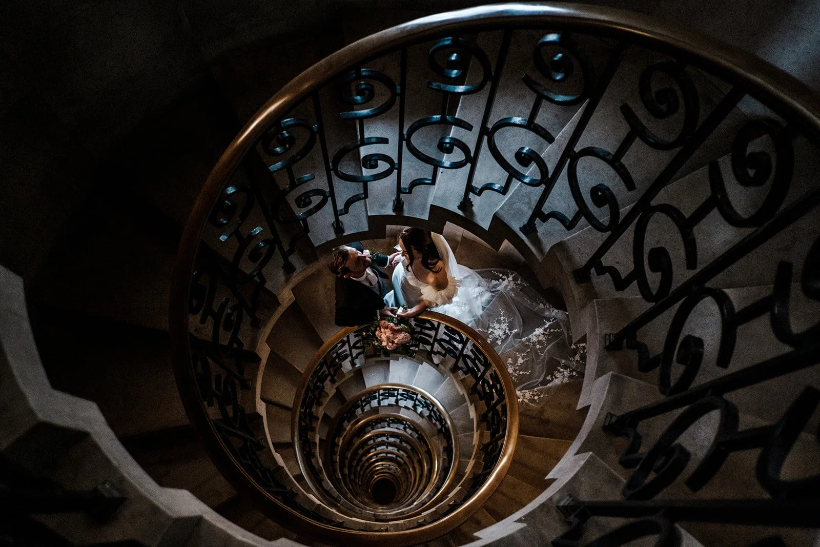 Jade and Adam photographed from above on the spiral staircase at The Ned Hotel