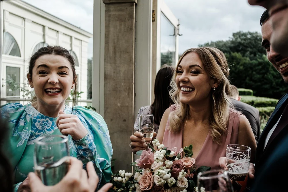 Bridesmaids laughing over a drink at the Clevedon Hall wedding reception