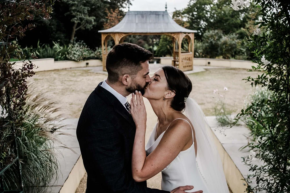 Sarah and Josh by the pavilion in the gardens at Clevedon Hall