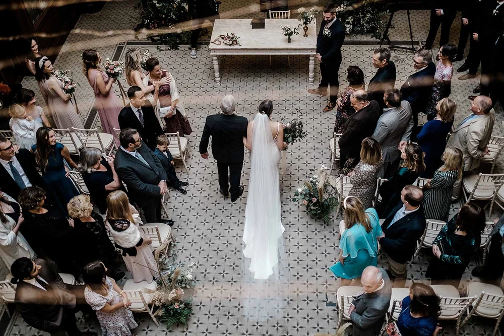 Sarah walking down the aisle in the grand hall at Clevedon Hall, North Somerset