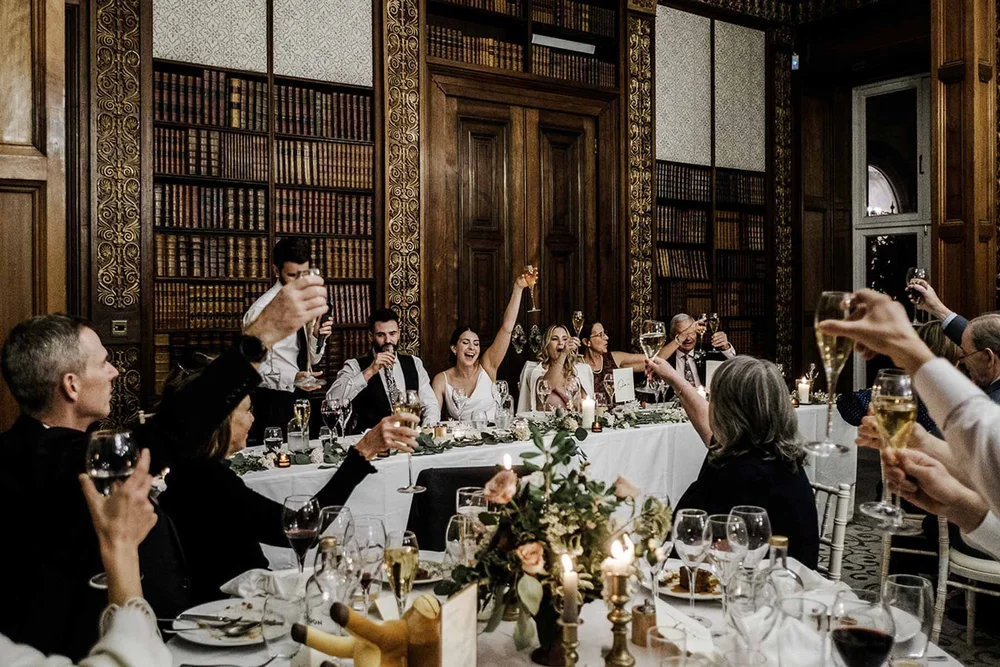 Guests toasting along the long table at the Clevedon Hall wedding breakfast