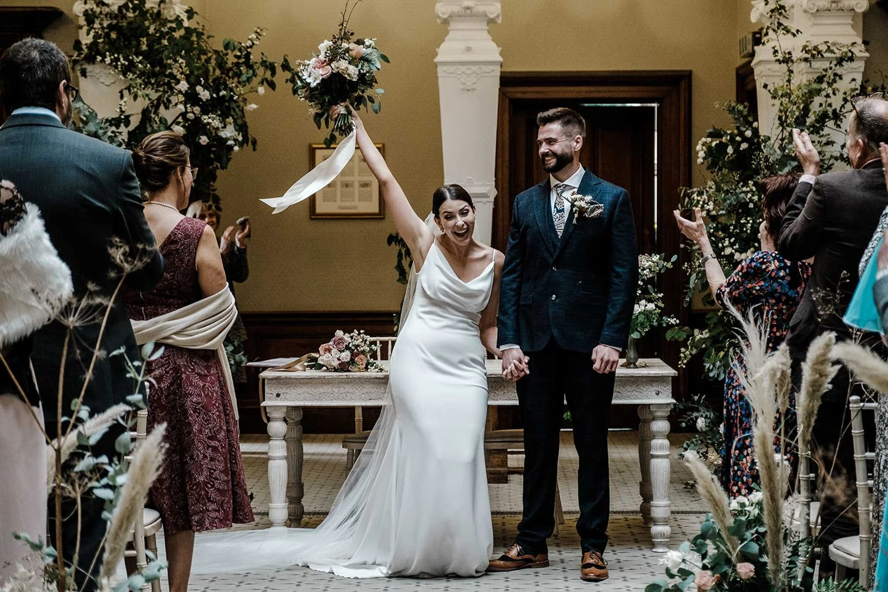 Sarah and Josh celebrating with the room after signing the register at Clevedon Hall, North Somerset