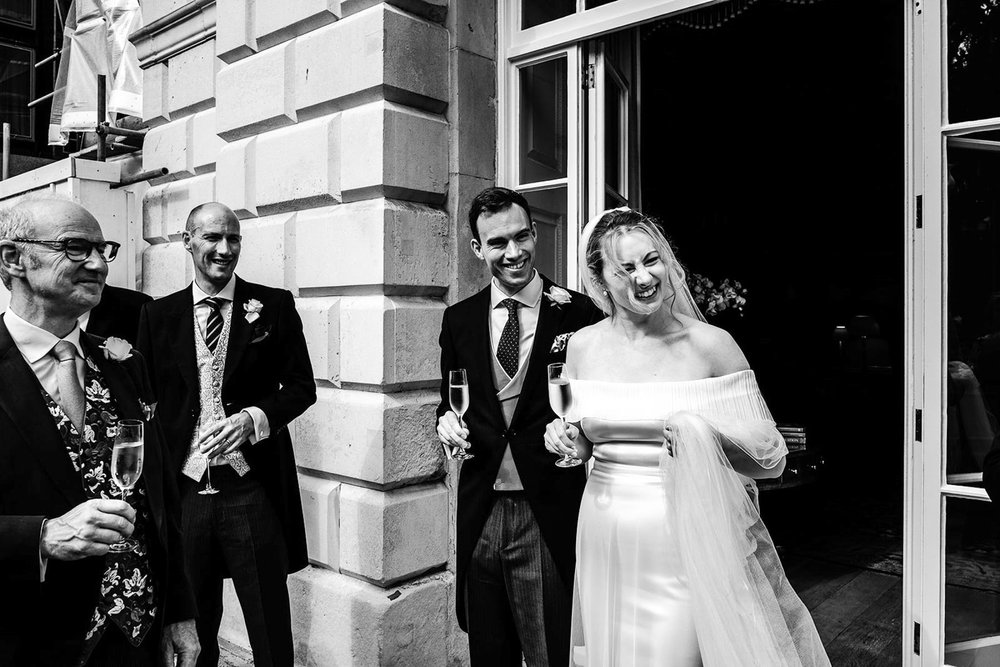 Black and white photograph of Gina and Ollie greeting guests outside Temple Church