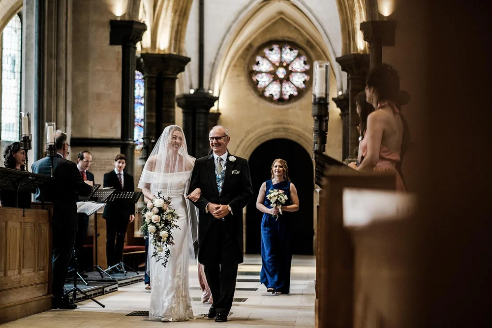 Gina walking down the aisle with her father beneath the rose window at Temple Church