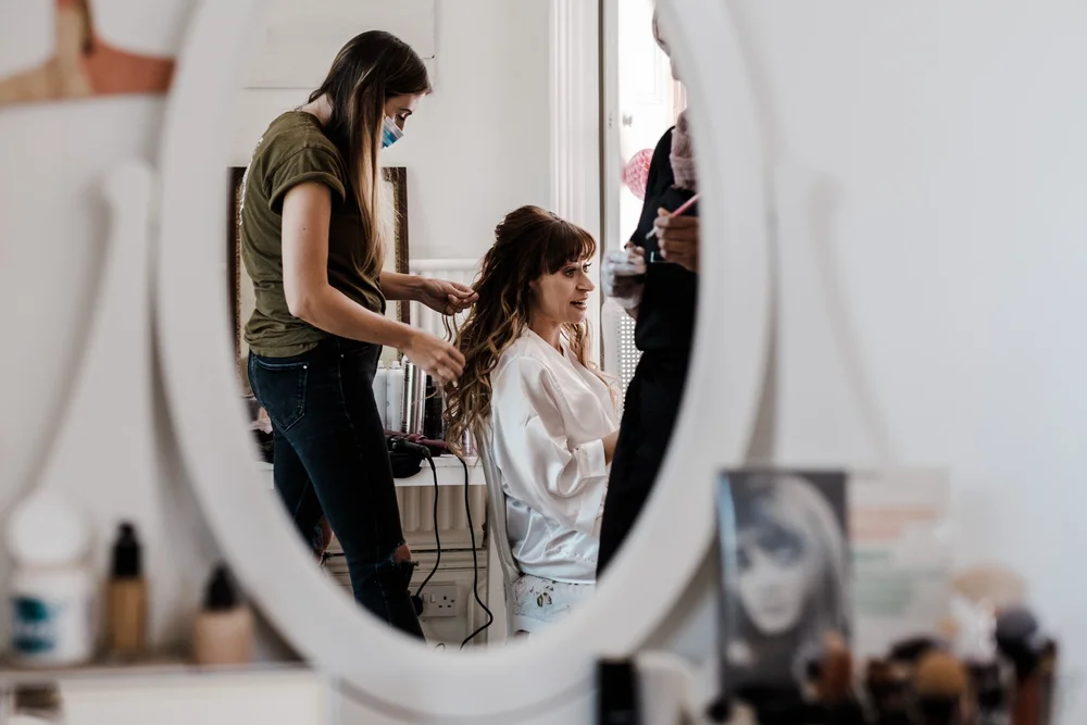 Jess having her hair done in front of the mirror on the morning of her Lyde Court wedding