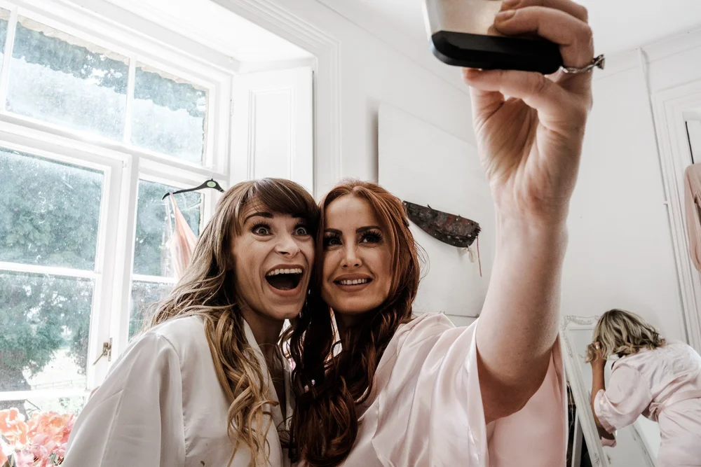 Jess and a bridesmaid laughing during preparations at Lyde Court