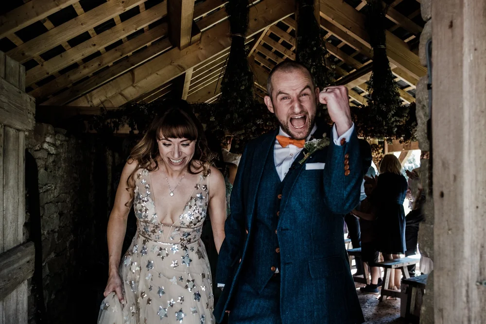 Jess and Tom walking back through the barn after their ceremony