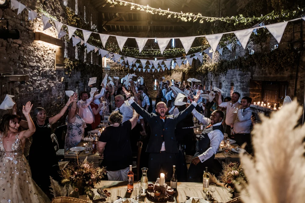 The barn at Lyde Court lit with bunting and festoon lights during the reception